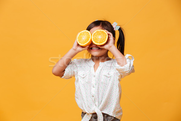 Little girl child covering eyes with orange. Stock photo © deandrobot