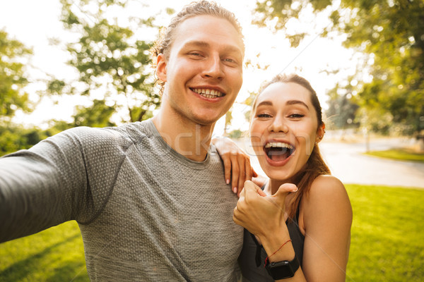 Photo of young happy couple man and woman 20s in tracksuits, tak Stock photo © deandrobot