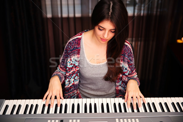 Young beautiful woman playing on piano at home Stock photo © deandrobot