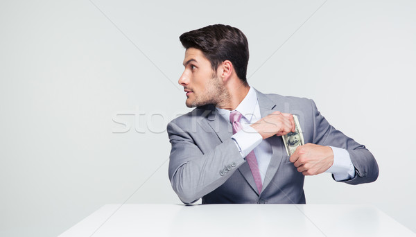 Businessman putting money in pocket  Stock photo © deandrobot