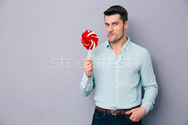 Drôle jeune homme lollipop gris regarder Photo stock © deandrobot