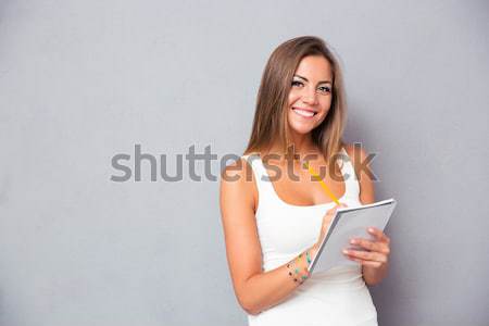 Smiling woman holding tablet computer Stock photo © deandrobot