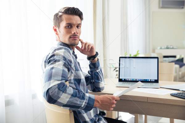 Man sitting at the table and checking bills Stock photo © deandrobot