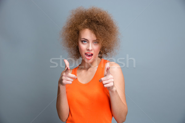 Positif heureux jeune femme pointant réussi orange [[stock_photo]] © deandrobot
