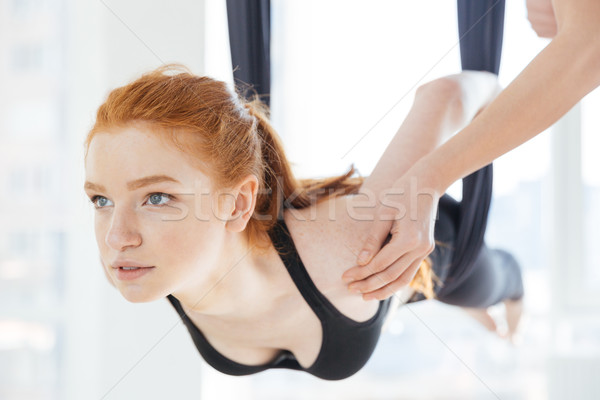 Stock photo: Beautiful woman doing pose of aerial yoga with personal trainer