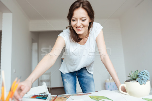 Happy woman painter working in art studio Stock photo © deandrobot