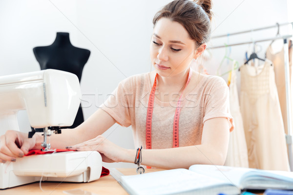 Concentrated woman seamstress sews on sewing machine  Stock photo © deandrobot