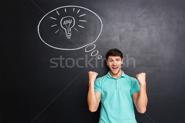 Cheerful successful young man having an idea and celebrating success Stock photo © deandrobot