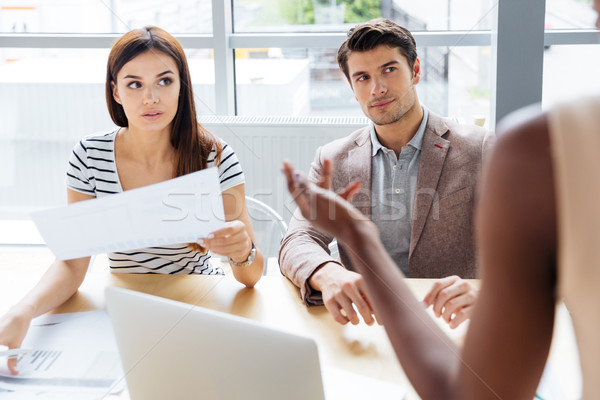 Stock photo: Three concentrated young businesspeople working with documents and using computer