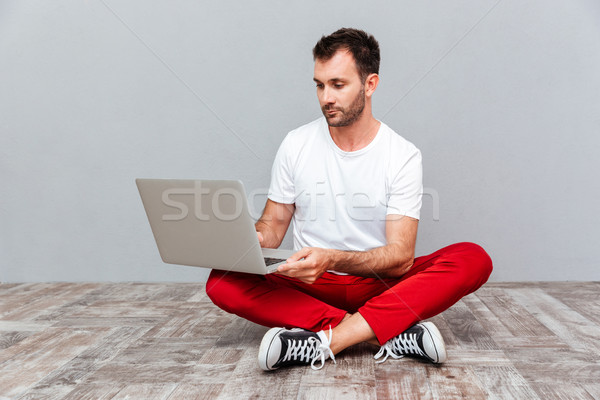 Pensieroso casuale uomo seduta piano laptop Foto d'archivio © deandrobot