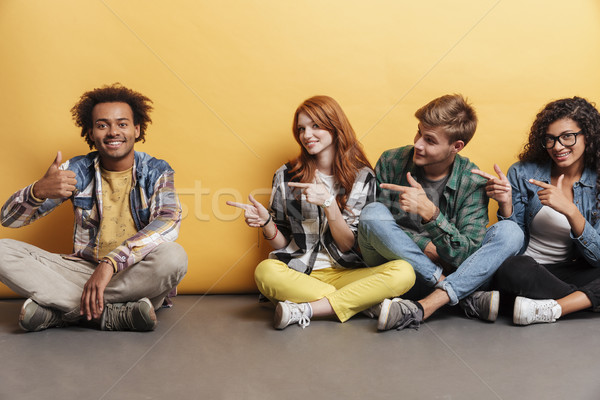 People sitting and pointing at cheerful man showing thumbs up Stock photo © deandrobot