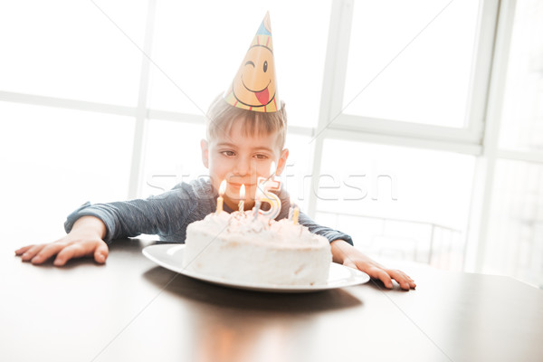 Happy birthday boy sitting in kitchen near cake while smiling Stock photo © deandrobot