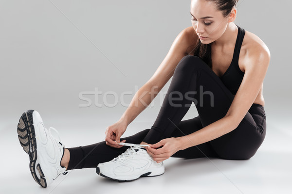 Mooie jonge vrouw atleet vergadering schoenveters grijs Stockfoto © deandrobot