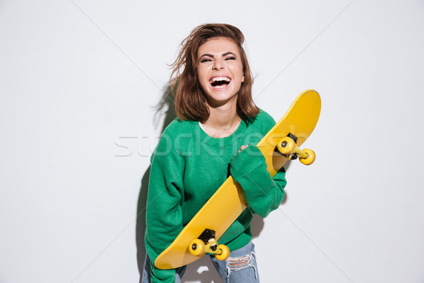 Pretty skater lady holding skateboard. Stock photo © deandrobot