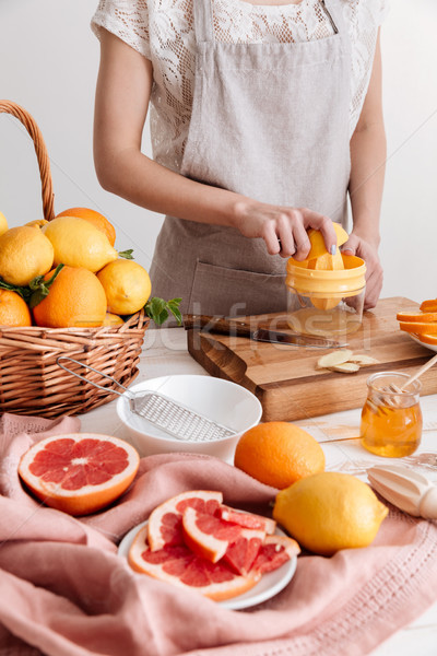 Cropped picture of woman squeezes out juice of a citruses. Stock photo © deandrobot