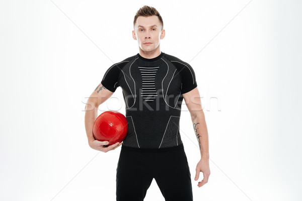 Portrait of a confident healthy sportsman holding red ...