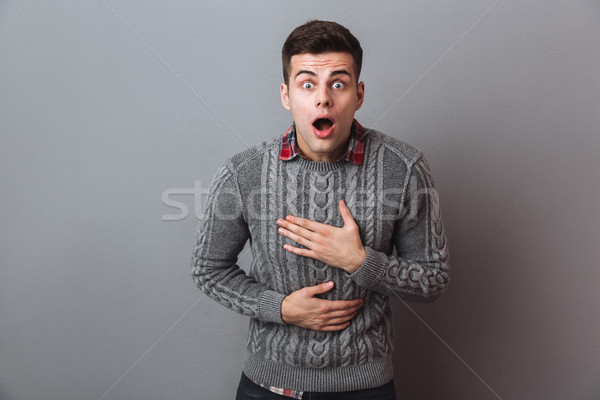 Shocked brunette man in sweater looking at the camera Stock photo © deandrobot