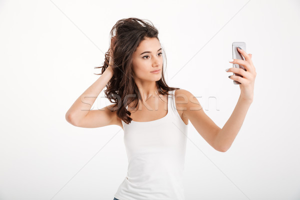 Portrait of a pretty girl dressed in tank-top taking a selfie Stock photo © deandrobot