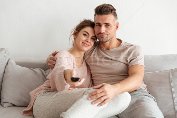 Portrait of an attractive young couple sitting on a couch Stock photo © deandrobot