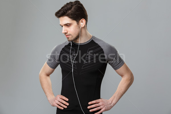 Handsome young sportsman listening music with earphones. Stock photo © deandrobot