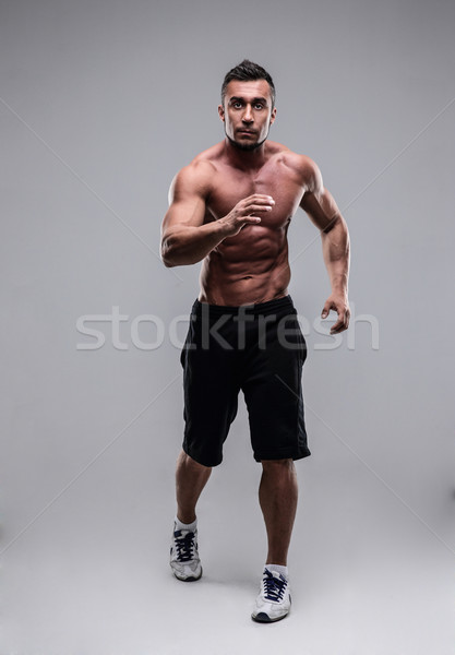 Portrait of a muscular man running over gray background Stock photo © deandrobot