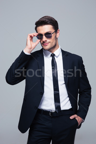 Porträt trendy Geschäftsmann Sonnenbrillen stehen grau Stock foto © deandrobot
