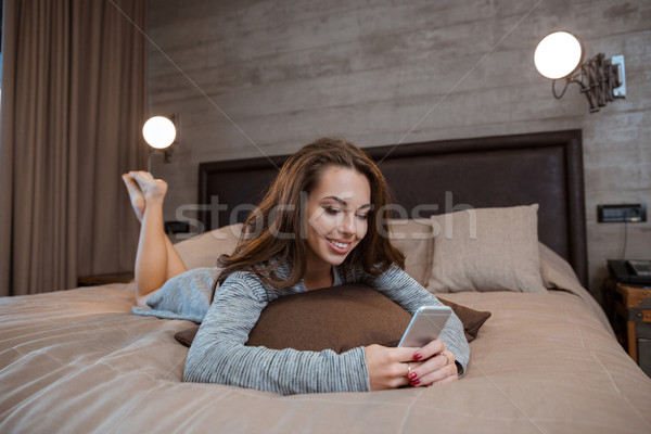 Woman lying on the bed and using smartphon Stock photo © deandrobot