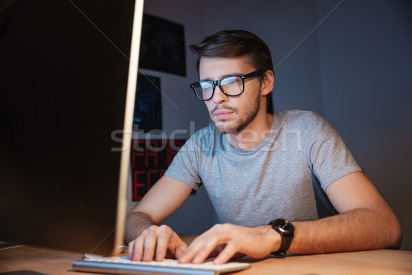Concentrated serious man in glasses using computer at home  Stock photo © deandrobot