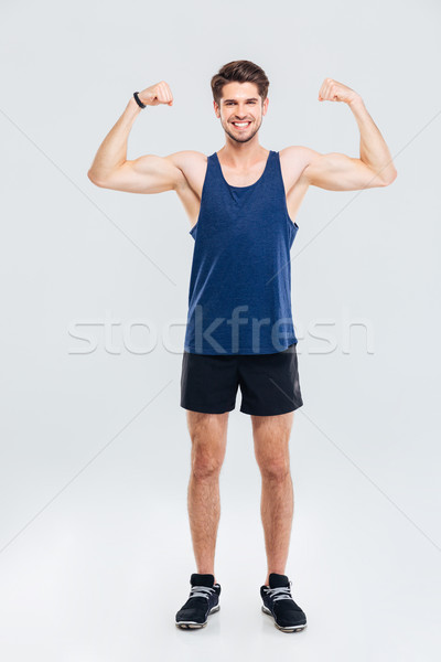 Teljes alakos portré mosolyog férfi mutat bicepsz Stock fotó © deandrobot