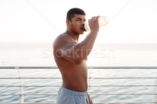 Półnagi Afryki człowiek sportowiec stałego woda pitna Zdjęcia stock © deandrobot