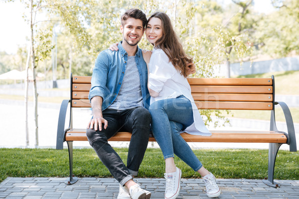 Happy young couple in love sitting on a park bench Stock photo © deandrobot