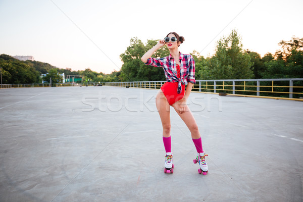 Girl in sunglasses and red swimsuit wearing roller skates outdoors Stock photo © deandrobot