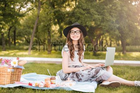 Sorridente bastante mulher jovem usando laptop piquenique parque Foto stock © deandrobot