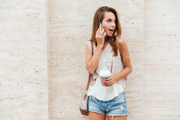 Stock photo: Girl talking on the mobile phone and drinking coffee