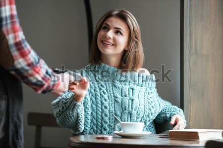 Cheerful young lady pays for her order with debit card. Stock photo © deandrobot