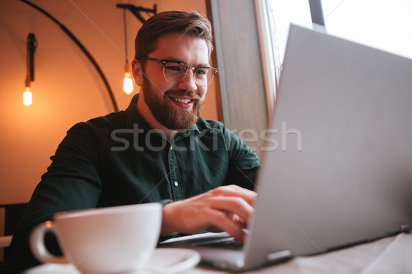 [[stock_photo]]: Souriant · barbu · jeune · homme · café · utilisant · un · ordinateur · portable · image