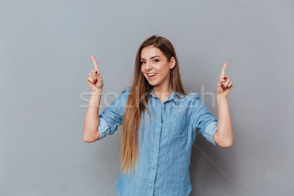 Feliz mujer camisa posando estudio senalando Foto stock © deandrobot