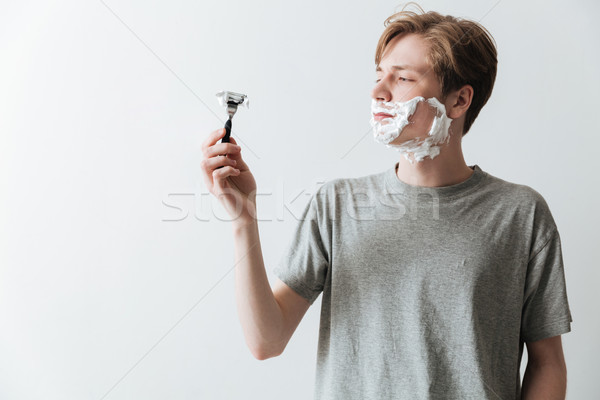 [[stock_photo]]: Jeune · homme · mousse · regarder · rasoir · tshirt · gris