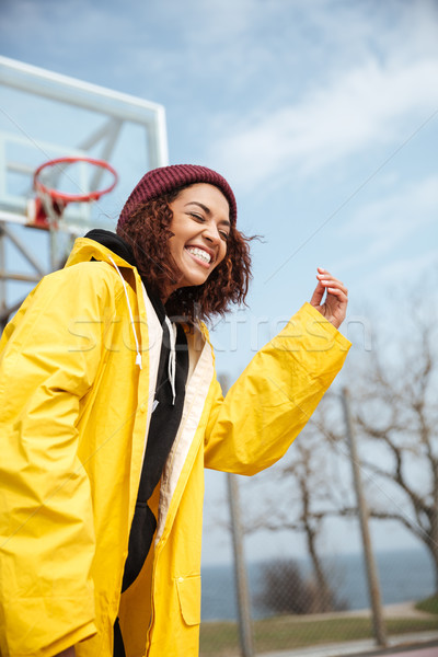 Laughing african curly young lady wearing yellow coat Stock photo © deandrobot