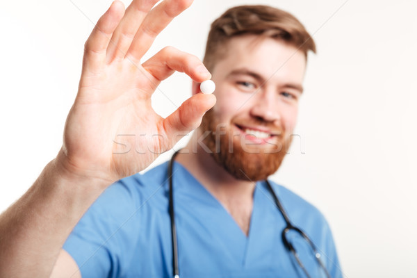 Portrait of a young male medical doctor offering a pill Stock photo © deandrobot