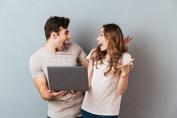Portrait of a cheery happy couple holding laptop computer Stock photo © deandrobot