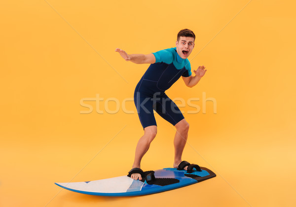 Image of Scared surfer in wetsuit using surfboard Stock photo © deandrobot