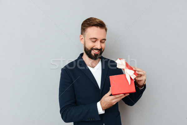 Happy young handsome man looking at red gift isolated Stock photo © deandrobot