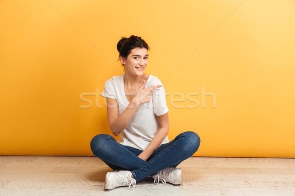 Portrait of a smiling young woman sitting with legs crossed Stock photo © deandrobot