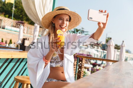 Photo of beautiful young woman 20s in straw hat and swimwear tak Stock photo © deandrobot