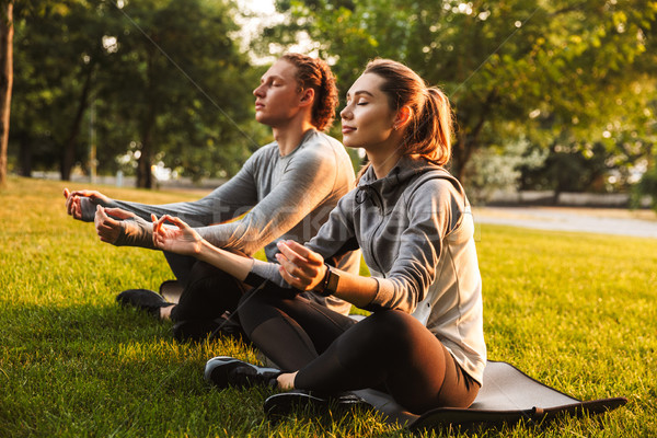 Fitness loving couple friends in park make meditate exercises. Stock photo © deandrobot