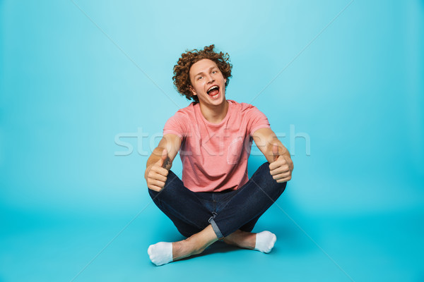 Portrait of a cheerful young curly haired man showing Stock photo © deandrobot