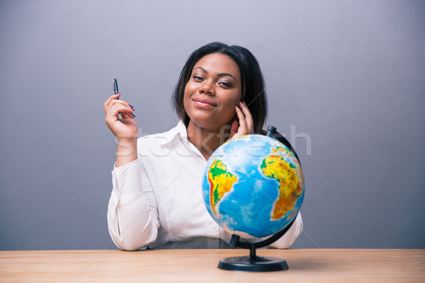 Businesswoman sitting at the table with pen and globe  Stock photo © deandrobot