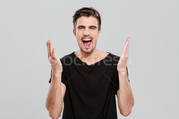 Portrait of young man screaming with hands up Stock photo © deandrobot