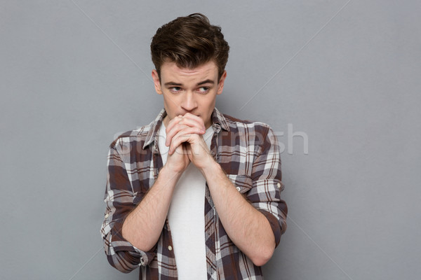 Scared young handsome guy waiting and praying Stock photo © deandrobot